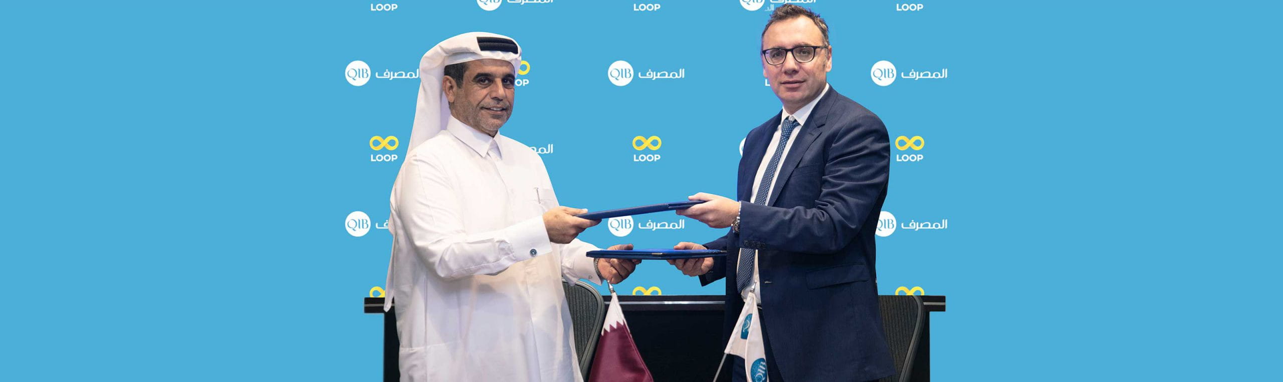 Award handover between two executives standing in front of an event backdrop.