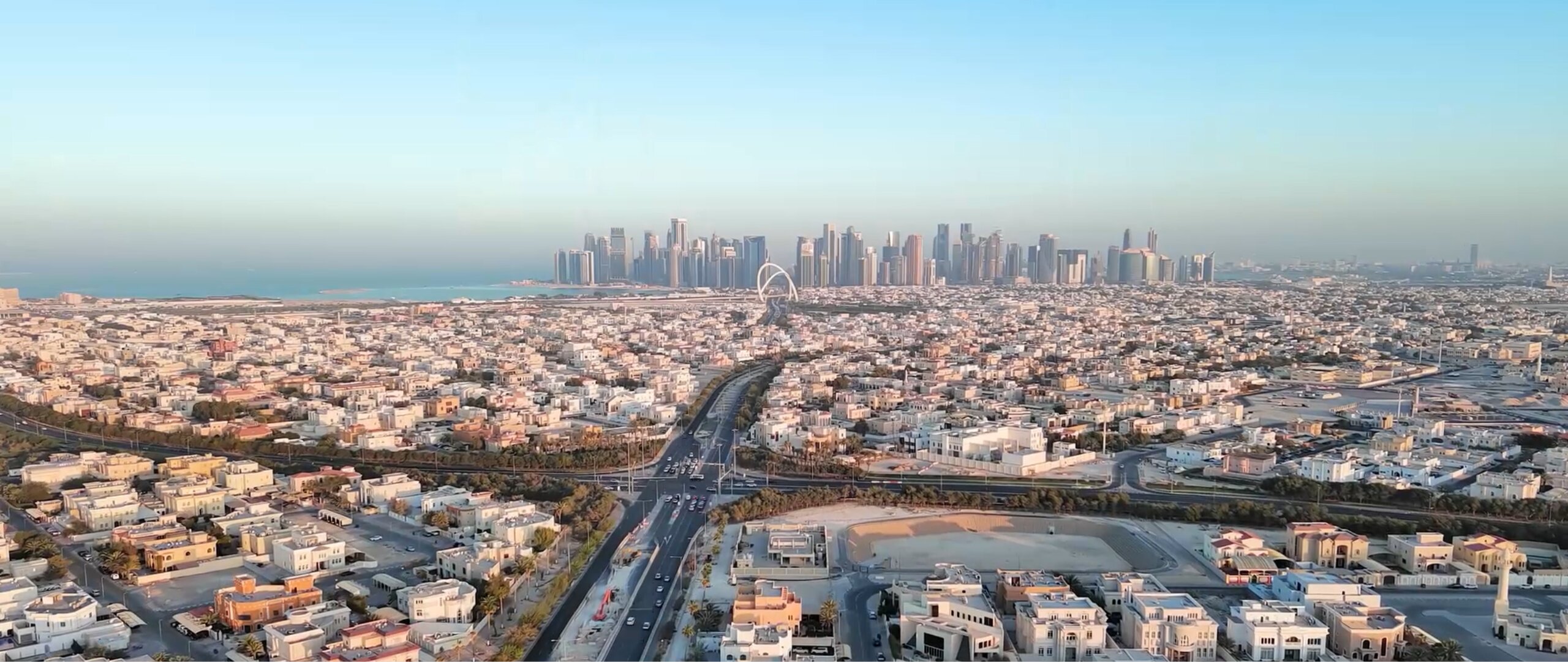 Aerial city view showing roads, buildings, and skyline.
