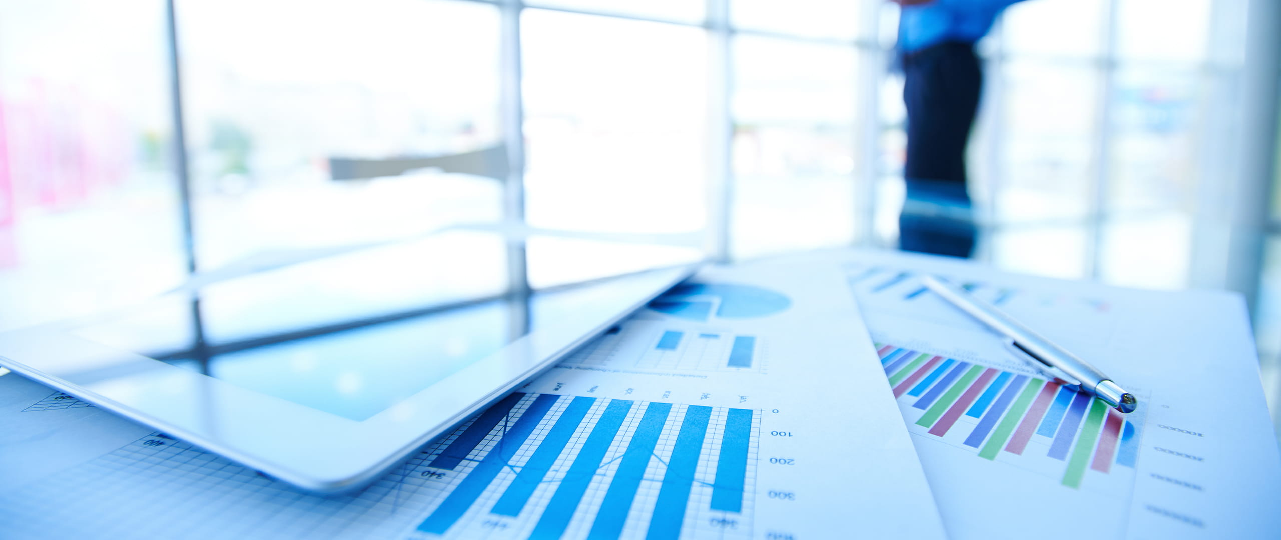 Printed business charts on a desk showing bar and line graphs, with a pen resting on the documents.